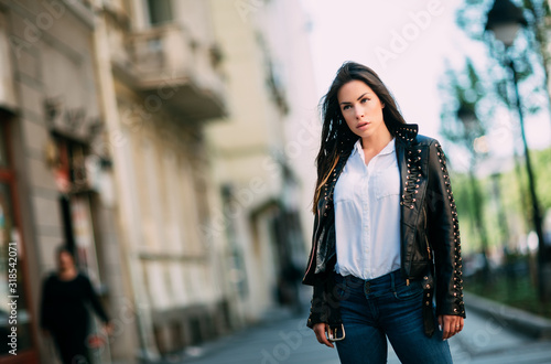Beautiful fashion model in black leather jacket posing outdoor.