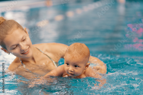 Mother and little son having fun in a swimming pool