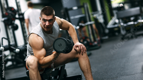 Fit man in sportswear focused on exercise for biceps in the gym