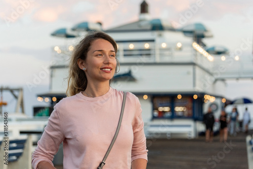 Fototapeta Naklejka Na Ścianę i Meble -  Happy blonde woman in pink sweater at the pier of Malibu