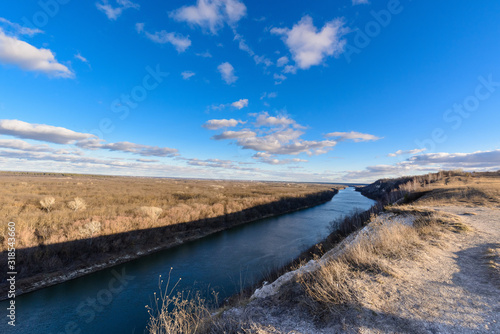 panorama of nature in early spring. river in the sun, cloudy blue sky at sunset