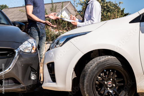 The car insurance agent is checking the accident spot. Of the customer, along with the form and customer signature for car claims And process the claim © Orathai