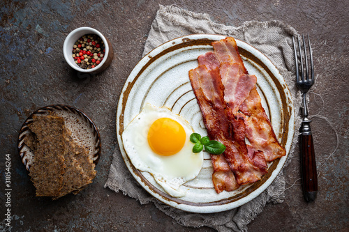 Fried eggs and bacon for breakfast on a plate, top view, copyspace