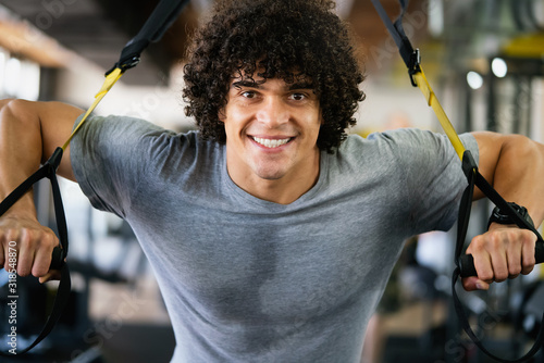 Handsome happy fit man exercising with suspension training trx photo