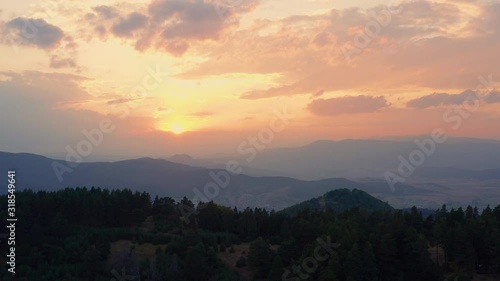 Wallpaper Mural Lens flare sun through tops of fir trees on panorama of mountains landscape at orange sunrise and bright disk of sun in morning in summer against blue sky with clouds aerial view. Drone ahead. Nature Torontodigital.ca