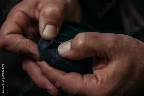 cropped view of shoemaker fixing leather to shoe in workshop
