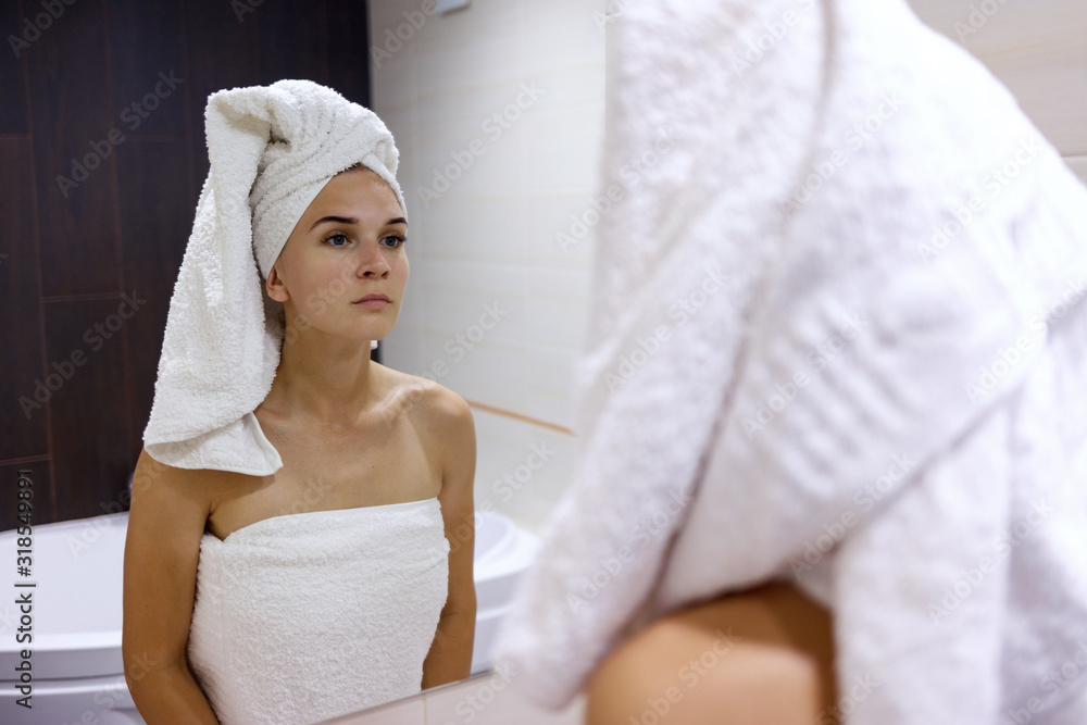 Young woman after shower looks in the mirror and admires herself. Young woman after shower looks in the mirror and admires herself.