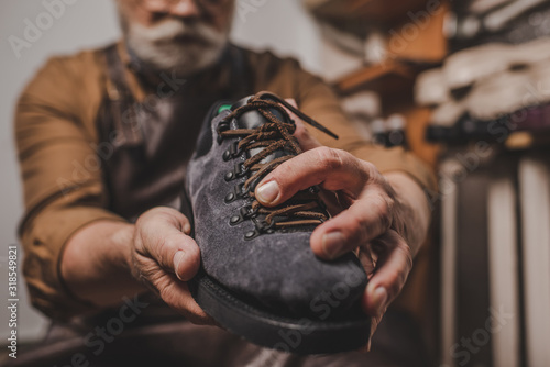 Selective focus of shoemaker holding suede shoe in workshop
