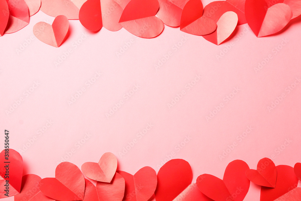 Cut out of red paper hearts on pink background.