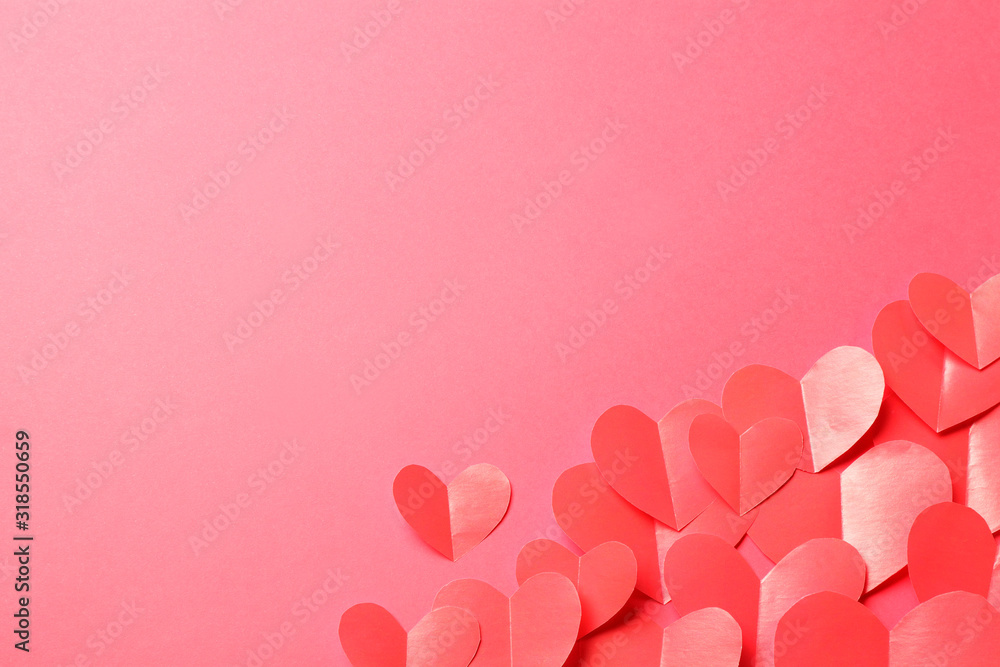 Cut out of red paper hearts on pink background.