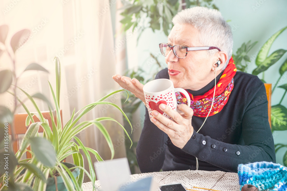 Old lady blowing a kiss, having her morning coffee and listening to her favorite song Old lady blowing a kiss, having her morning coffee and listening to her favorite song