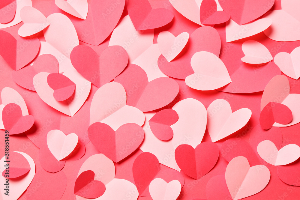 Bunch of cut out of pink and red paper hearts on red background