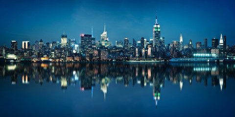 Panorama of the skyline of Manhattan, view from Jersey city during the blue hour. New York City skyline  with the Empire State building at night with  water reflections.