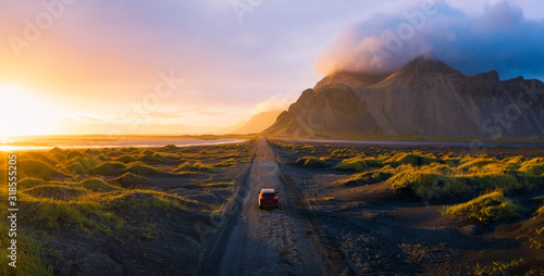 Fototapeta Gravel road at sunset with Vestrahorn mountain and a car driving, Iceland