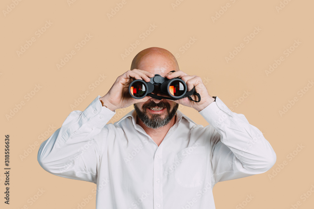 Serious middle-aged man with folded arms and a deadpan expression posing in front of a beige background with copy space Serious middle-aged man with folded arms and a deadpan expression posing in front of a beige background with copy space