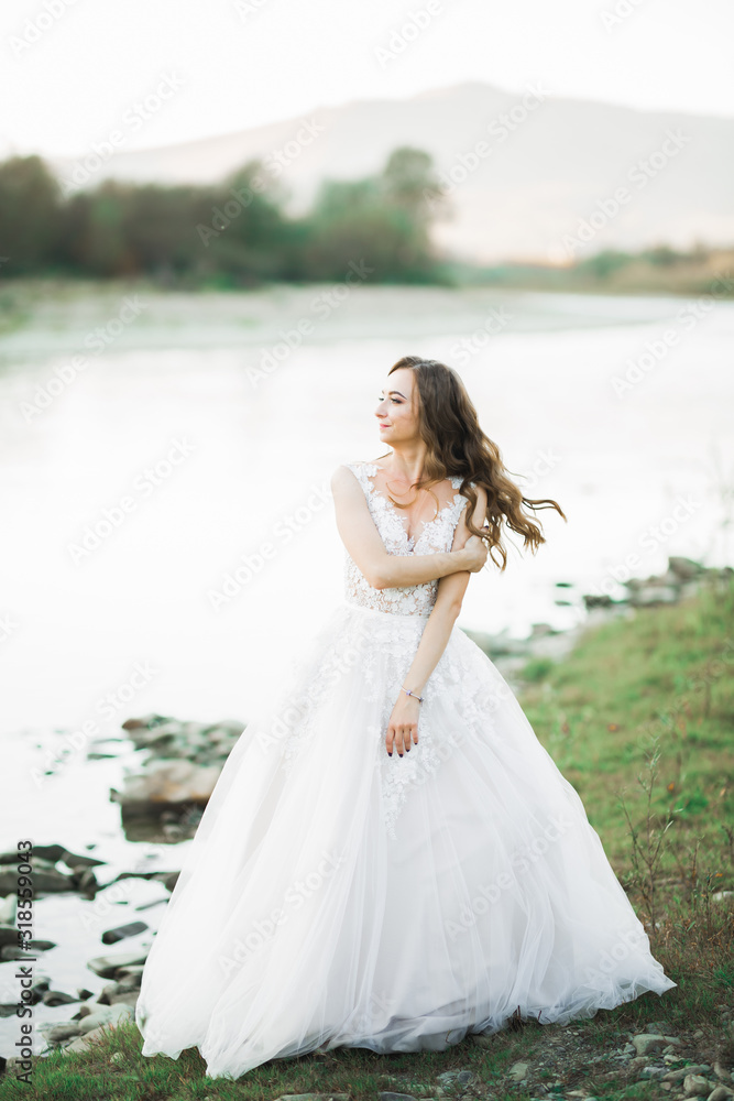 Portrait of stunning bride with long hair standing by the river