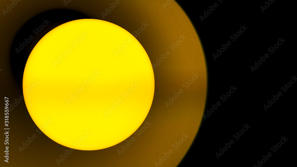 Close-up of a lamp with yellow light on a black background.