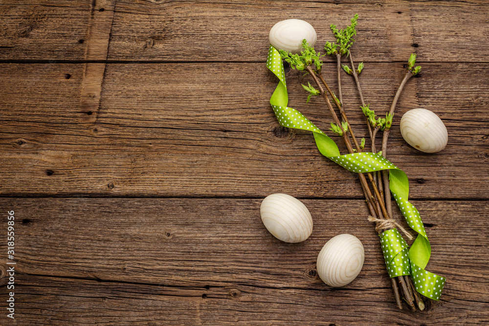 Zero waste Easter concept. Spring twigs with fresh green leaves, wooden eggs, polka dot ribbon. Old vintage wooden boards background