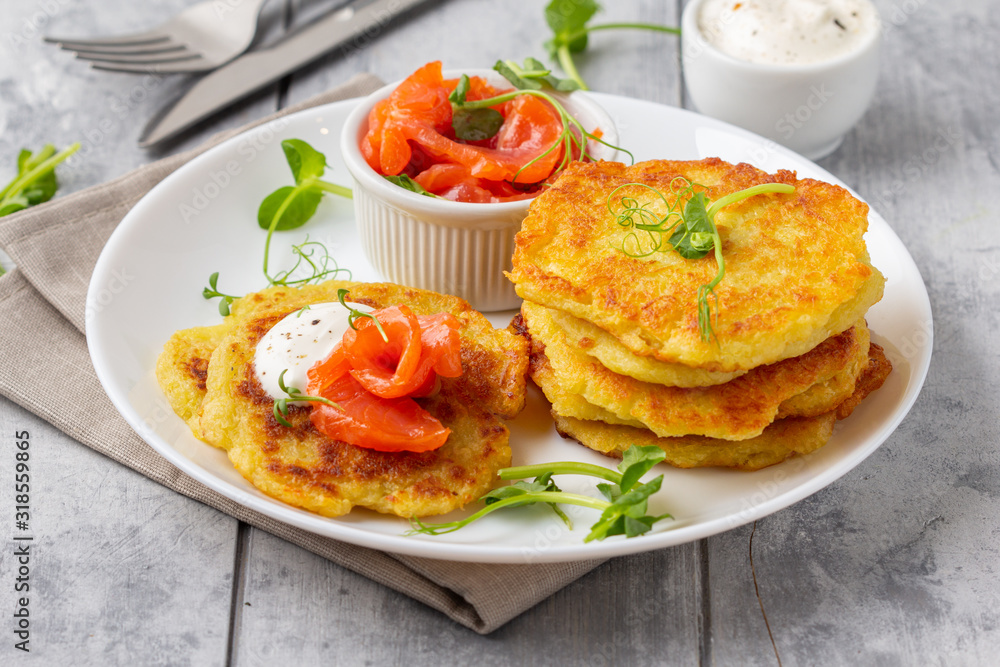 Fried potato pancakes with salmon and sour cream, fritter, roesti, golden crispy crust. Traditional delicious food