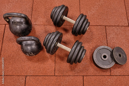 Fototapeta Naklejka Na Ścianę i Meble -  Dumbbells and kettlebells on a floor. Bodybuilding equipment. Fitness or bodybuilding concept background. Photograph taken from above, top view