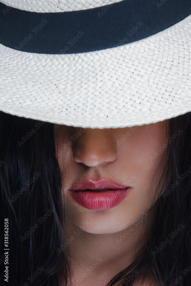 Fashion pretty young woman wearing a white straw hat in studio on a grey background Fashion pretty young woman wearing a white straw hat in studio on a grey background