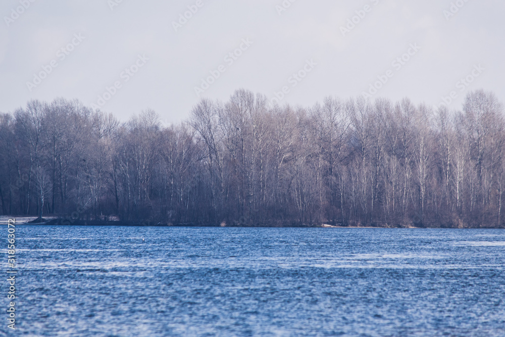 Winter landscape with trees and lake. Blue river and forest without leaves. Winter landscape with trees and lake. Blue river and forest without leaves.