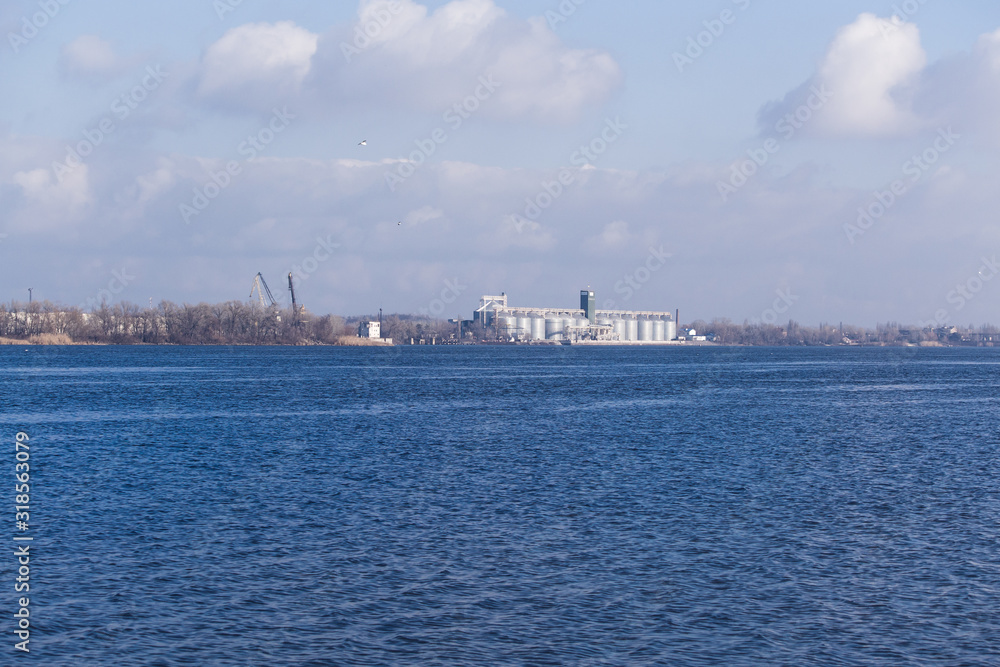 Winter landscape on the river coast. River with blue sky and clouds.