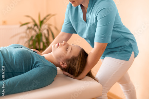 Female physiotherapist or a chiropractor adjusting patients neck. Physiotherapy, rehabilitation concept. Side view cropped shot. photo