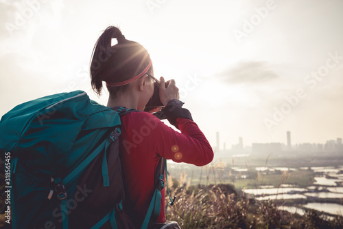 Female photographer taking photo on mountains next to modern city