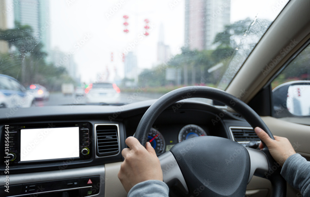 People hands holding steering wheel while driving car on city road in rainy day People hands holding steering wheel while driving car on city road in rainy day