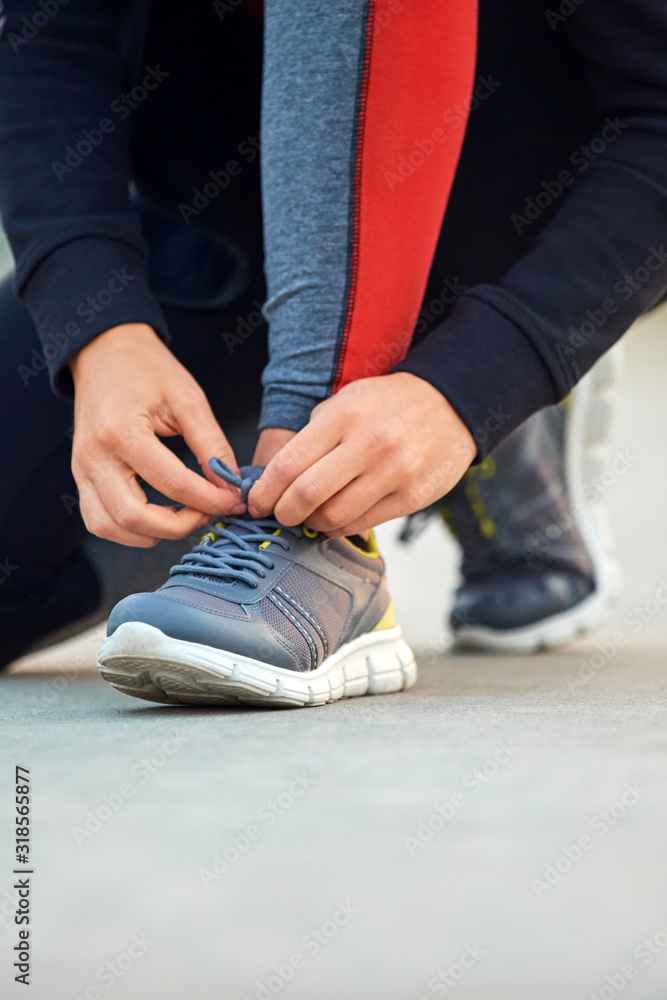 Fototapeta premium Sporty woman tying running shoes in urban park.