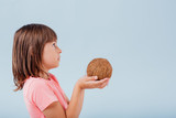 girl with coconut in hand. isolated on blue background, copy space, in studio, profile view