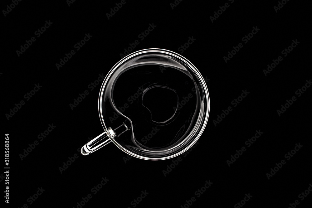 Glass cup in the form of a heart in the light, on a black background, top view Glass cup in the form of a heart in the light, on a black background, top view