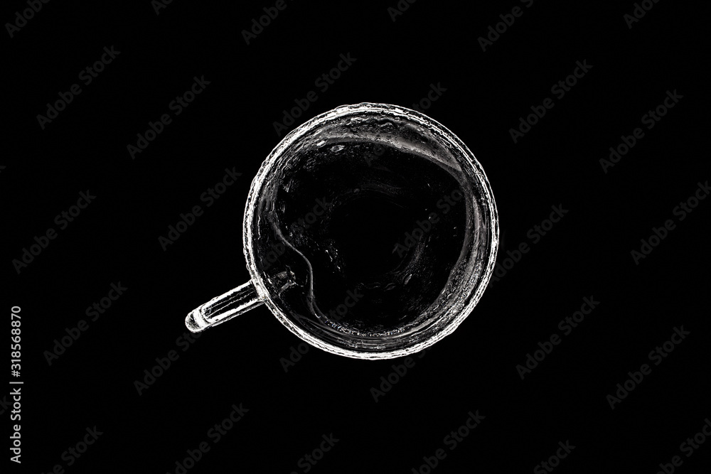 Glass cup in the form of a heart with drops of water in the light, on a black background, top view Glass cup in the form of a heart with drops of water in the light, on a black background, top view