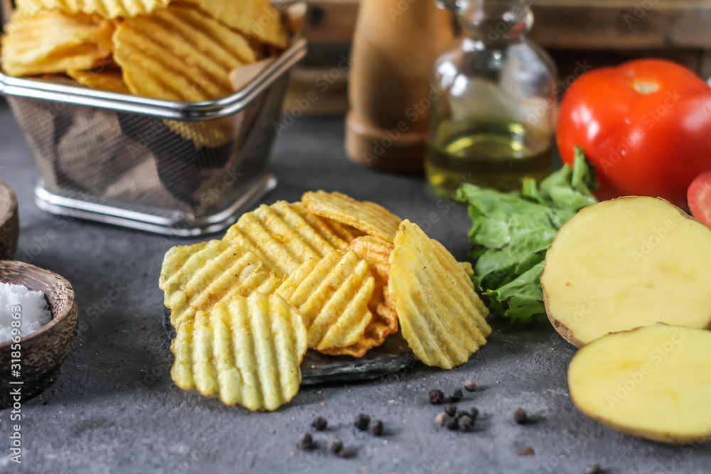 Photo of potato chips on the table with ingredients around. Raw potato tomato. Salt black pepper. On a wooden table. Retro background. On dark board. Studio photography. Image Photo of potato chips on the table with ingredients around. Raw potato tomato. Salt black pepper. On a wooden table. Retro background. On dark board. Studio photography. Image