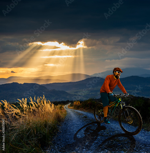 Cycling man riding on bike at sunset mountains forest landscape. Cycling MTB enduro flow trail track. Outdoor sport activity. photo