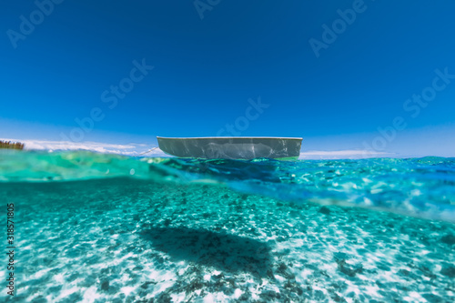 Tropical turquoise ocean water with sandy bottom underwater and boat