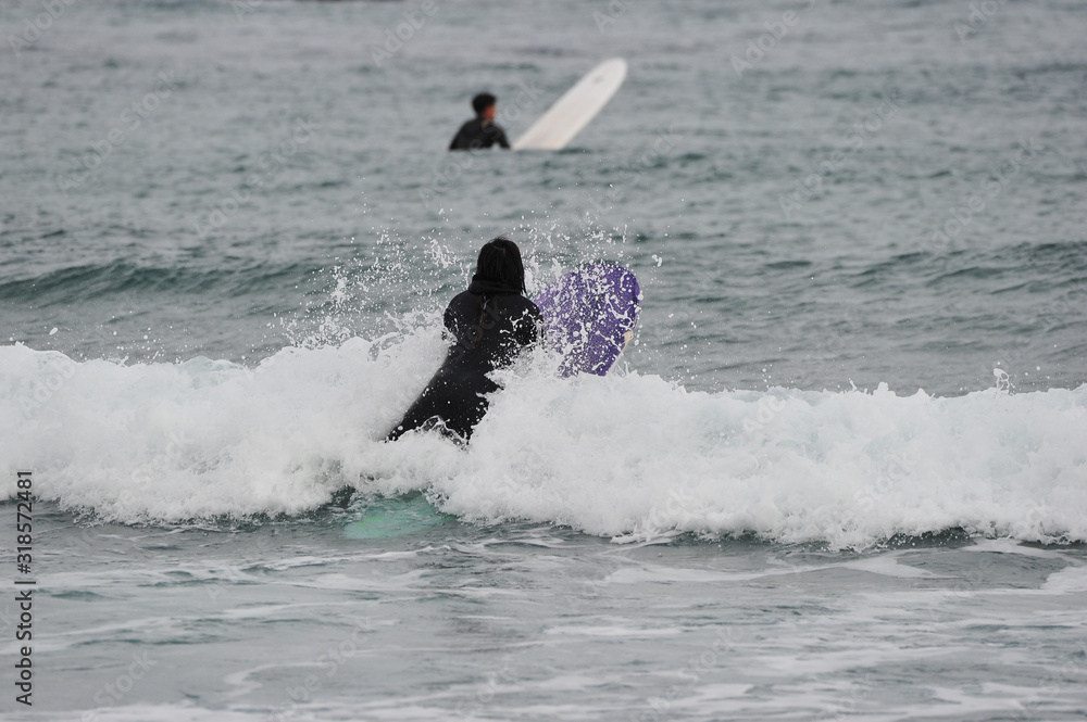 Fototapeta premium Korean Winter surfers at the Buheung-ri beach in Namjeong-Myeon, Yeongdeok-gun, South Korea.