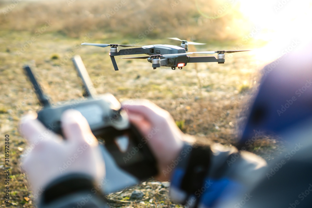 Man operating drone / man holding remote control drones / drone controller.  Photos | Adobe Stock