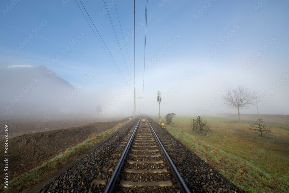 Railroad Tracks in the Fog and Mountain in Ticino, Switzerland.