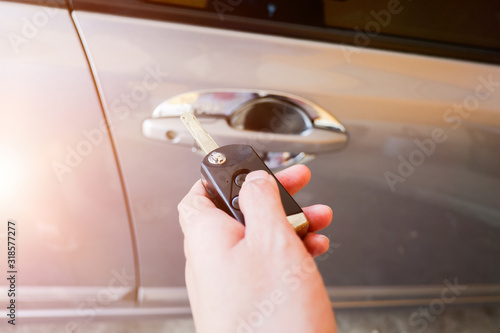 Cropped shot view of woman’s Hand holding a car key and opening the car door lock.