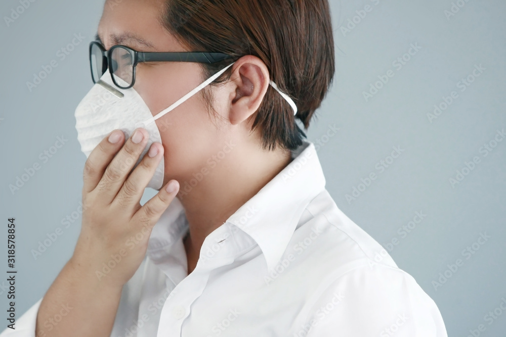 A asian woman wearing a germ protection mask in a white shirt with gray background A asian woman wearing a germ protection mask in a white shirt with gray background