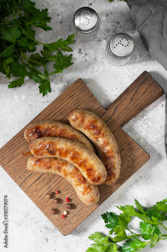 Grilled sausages on a wooden Board on a light gray kitchen table. View top
