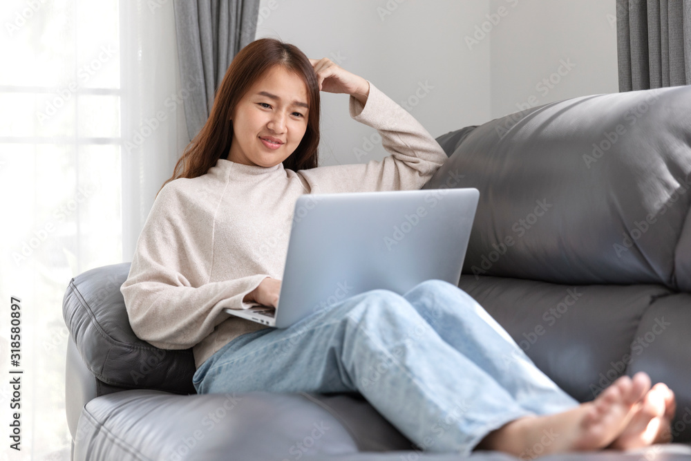 Young woman doing research work for her business, Smiling woman sitting on sofa relaxing while browsing online shopping website. Young woman doing research work for her business, Smiling woman sitting on sofa relaxing while browsing online shopping website.