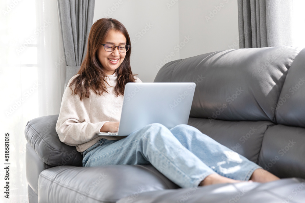 Young woman doing research work for her business, Smiling woman sitting on sofa relaxing while browsing online shopping website. Young woman doing research work for her business, Smiling woman sitting on sofa relaxing while browsing online shopping website.