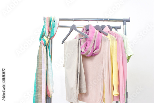 Spring fashion - pastel colored clothes on rail. Female colorful bright spring clothing set of on the racks on white background. Sale at clothing store concept.