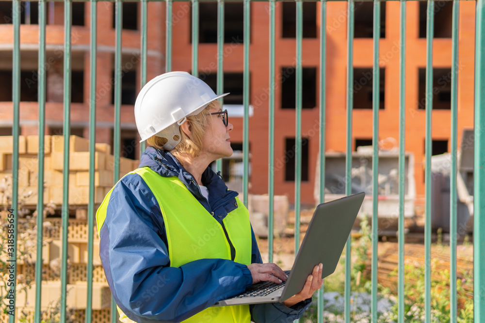 A woman Builder at a construction site inspects a house made of brick A woman Builder at a construction site inspects a house made of brick