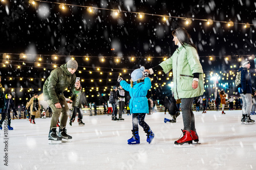 Street skating rink. Family at the ice rink. Father takes video on smartphone.