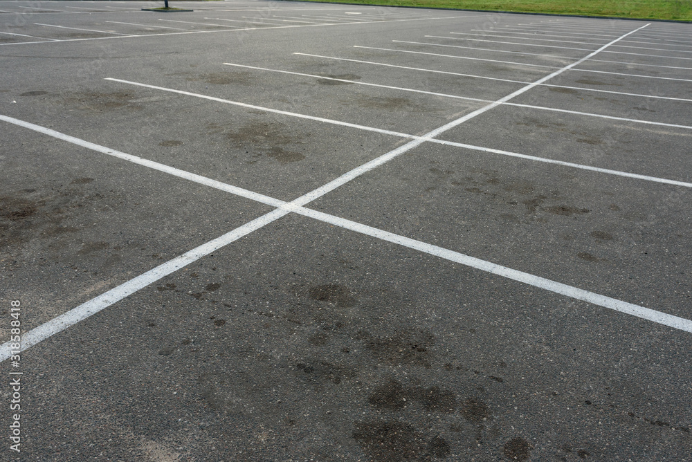  Empty outdoor dirty parking lot space marked with white lines.