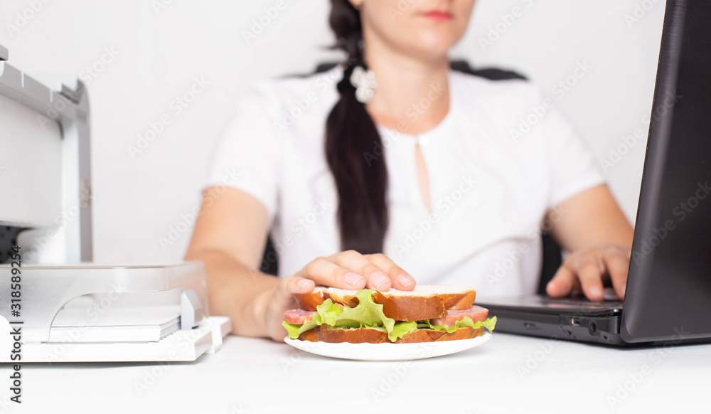 Caucasian girl office worker holds hand for a sandwich during a working day. Concept of malnutrition in the office.